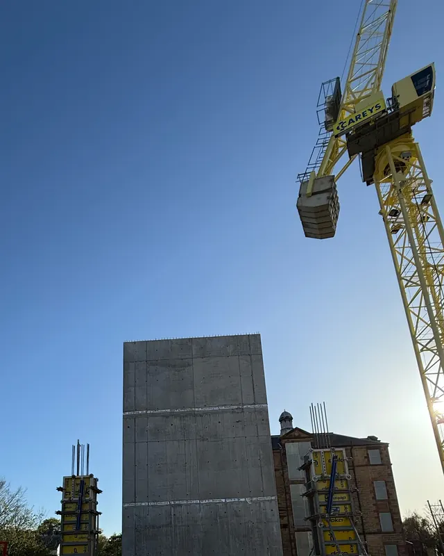 CAREYS tower crane beside a concrete core, sun behind the jib